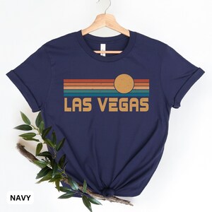 May include: Navy blue t-shirt with a retro sunset graphic and the text "LAS VEGAS" in a vintage font.