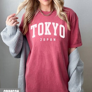 Pode incluir: Uma camiseta vermelha carmim com o texto "TOKYO JAPAN" em branco.