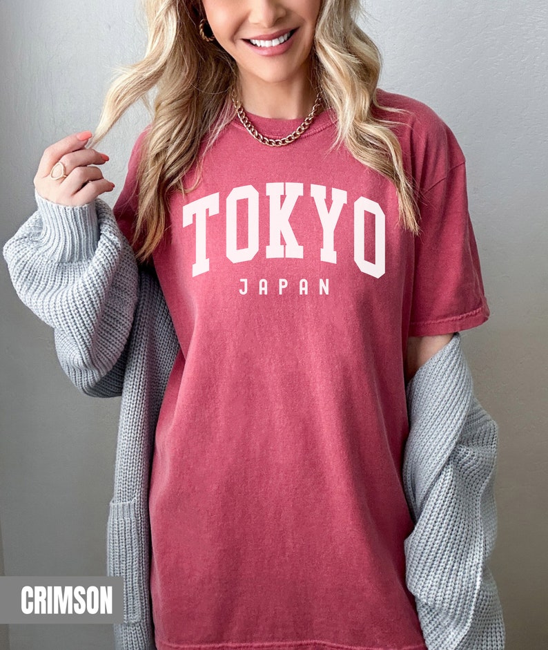 Pode incluir: Uma camiseta vermelha carmim com o texto "TOKYO JAPAN" em branco.