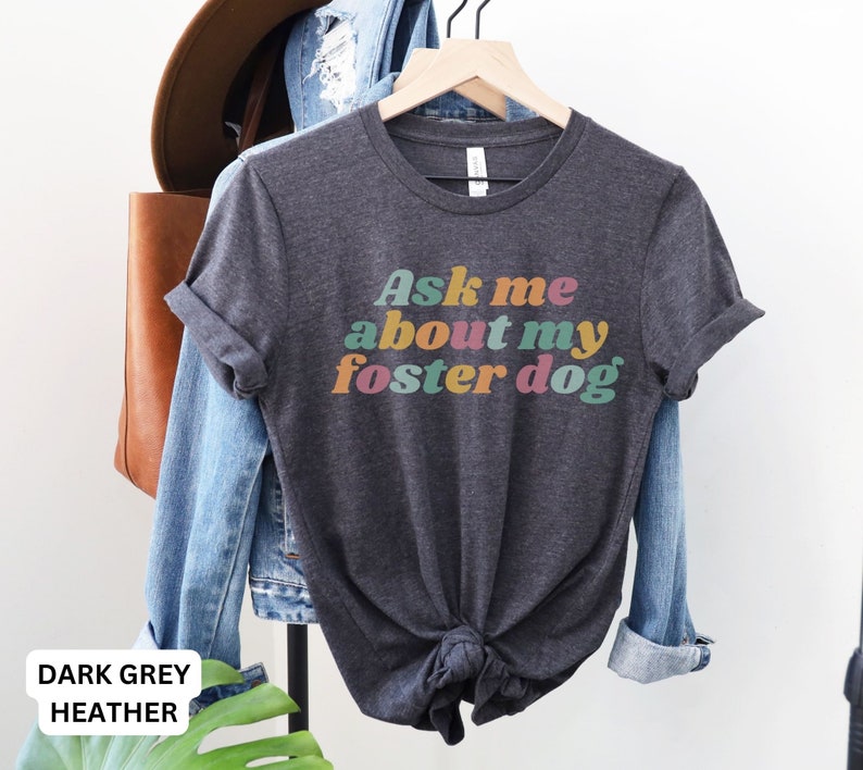 May include: Dark grey heather t-shirt with the text "Ask me about my foster dog" in colorful retro font.