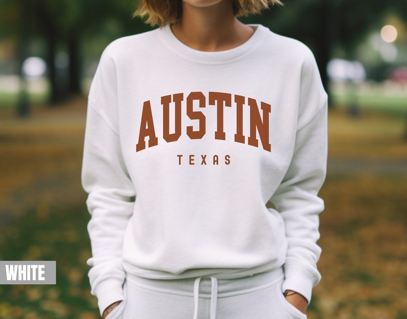 May include: White sweatshirt with a brown "AUSTIN TEXAS" graphic on the front.