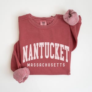 May include: A maroon sweatshirt with the text "NANTUCKET MASSACHUSETTS" in white.