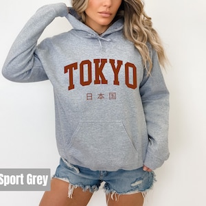 May include: A heather grey hoodie with a brown print of the word "TOKYO" and the Japanese characters for "Japan" underneath.