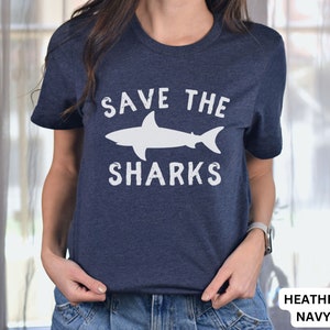 May include: A navy blue t-shirt with a white graphic of a shark and the text "Save the Sharks".