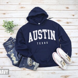 May include: Navy blue hooded sweatshirt with white text that reads "Austin Texas".