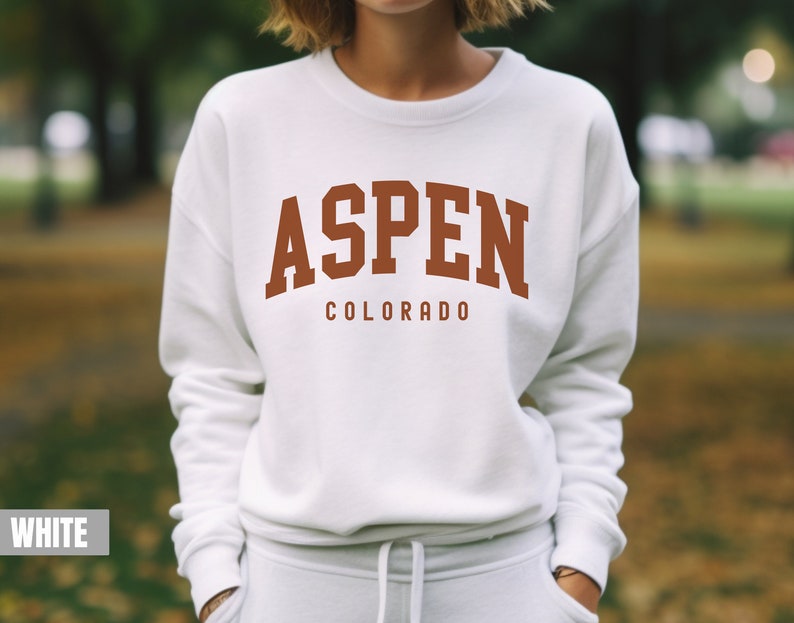 May include: White sweatshirt with a brown graphic that says "ASPEN COLORADO" in a collegiate font.