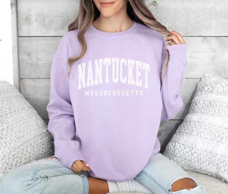 May include: A lavender sweatshirt with the text "NANTUCKET MASSACHUSETTS" in white.