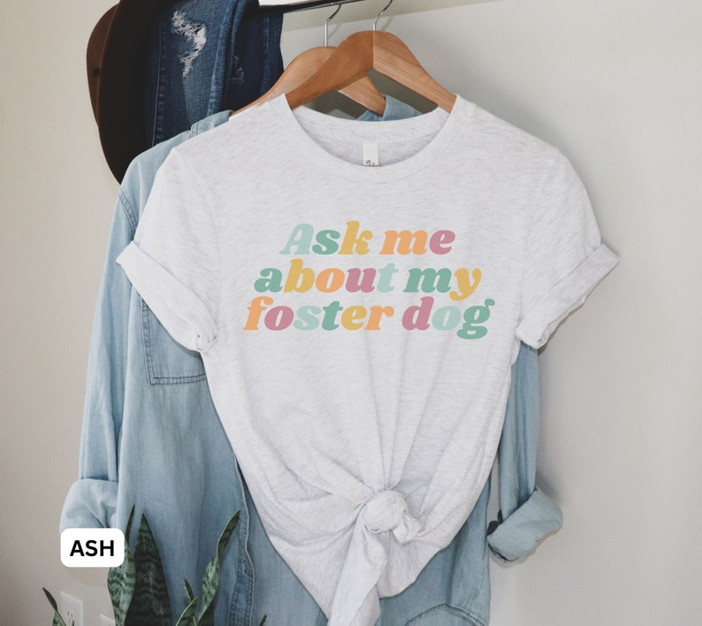 May include: A light gray t-shirt with the text "Ask me about my foster dog" in colorful retro-style lettering.