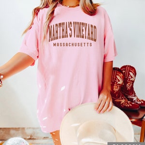 May include: A pink t-shirt with the text "Martha's Vineyard Massachusetts" in brown lettering.
