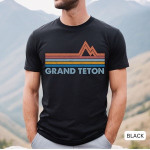 Puede incluir: Camiseta negra con un gr&aacute;fico retro de una cordillera y el texto "GRAND TETON" en blanco.