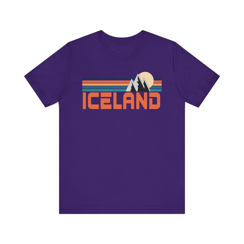 Puede incluir: Camiseta de manga corta de color morado con un gr&aacute;fico retro de monta&ntilde;as, un sol y la palabra "ICELAND" en naranja.