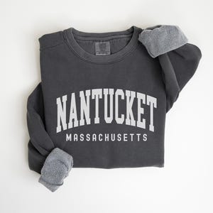May include: A dark gray sweatshirt with the text "NANTUCKET MASSACHUSETTS" in white.