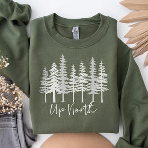 May include: A green sweatshirt with a silver print of pine trees and the text "Up North".