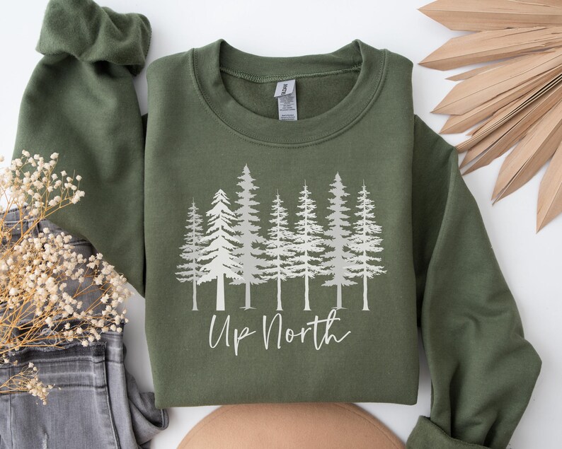 May include: A green sweatshirt with a silver print of pine trees and the text "Up North".
