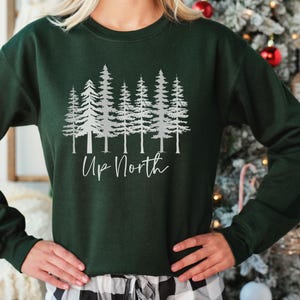 May include: A dark green sweatshirt with a silver print of a row of pine trees and the text "Up North".