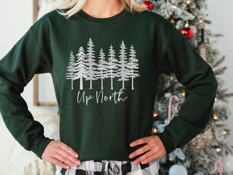 May include: A dark green sweatshirt with a silver print of a row of pine trees and the text "Up North".