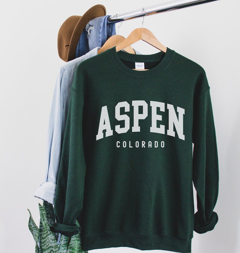 May include: A dark green sweatshirt with white text that reads "ASPEN COLORADO".