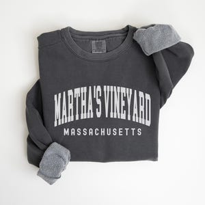 May include: A charcoal gray sweatshirt with the text "MARTHA'S VINEYARD MASSACHUSETTS" in white.