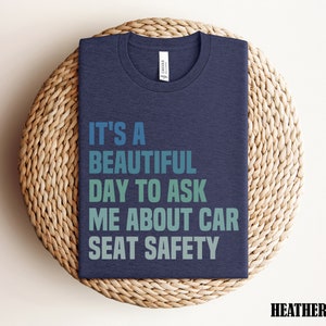 K&ouml;nnte beinhalten: T-Shirt in Dunkelblau mit dem Text "It's a beautiful day to ask me about car seat safety" in einem Farbverlauf von Blau, Gr&uuml;n und T&uuml;rkis.
