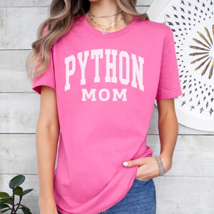 Peut inclure: T-shirt rose avec un texte blanc qui dit "PYTHON MOM".