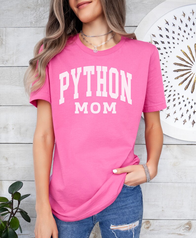 Peut inclure: T-shirt rose avec un texte blanc qui dit "PYTHON MOM".