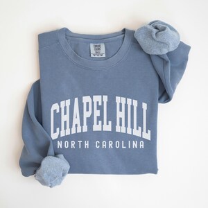 May include: A blue sweatshirt with the text "Chapel Hill North Carolina" in white.