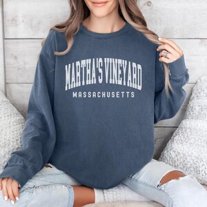 May include: A navy blue long-sleeved sweatshirt with the text "Martha's Vineyard Massachusetts" printed in white.