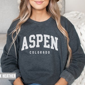 May include: Dark heather grey sweatshirt with white text that reads "Aspen Colorado" in a collegiate font.