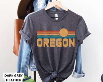 May include: Dark grey heather t-shirt featuring a retro sunset graphic and the word "OREGON" in yellow.