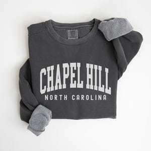 May include: A charcoal gray sweatshirt with the text "CHAPEL HILL NORTH CAROLINA" in white.