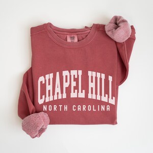 May include: A maroon sweatshirt with the text "Chapel Hill North Carolina" in white.