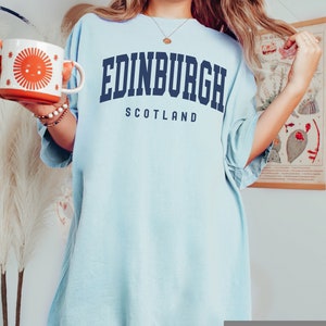 K&ouml;nnte beinhalten: Ein &uuml;berdimensioniertes hellblaues T-Shirt mit dem Text "EDINBURGH SCOTLAND" in Marineblau. Das Shirt ist aus einem weichen, bequemen Stoff und hat eine lockere Passform.
