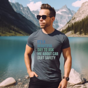 K&ouml;nnte beinhalten: Ein dunkelblaues T-Shirt mit einem verblassten blauen und gr&uuml;nen Aufdruck, auf dem steht "Es ist ein wundersch&ouml;ner Tag, um mich nach der Sicherheit von Autositzen zu fragen."