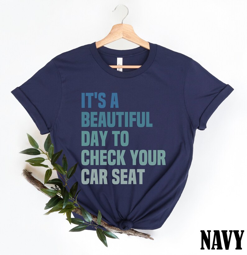 May include: Navy blue t-shirt with the text "It's a beautiful day to check your car seat" in a gradient of blue and green.