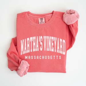 May include: A coral pink sweatshirt with the text "MARTHA'S VINEYARD MASSACHUSETTS" in white.