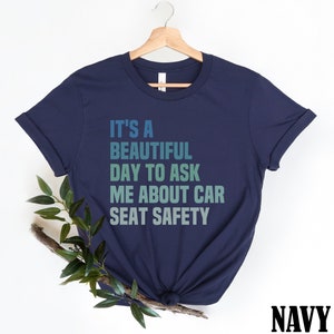 K&ouml;nnte beinhalten: Marineblaues T-Shirt mit dem Text "It's a beautiful day to ask me about car seat safety" in einem Farbverlauf von Blau und Gr&uuml;n.