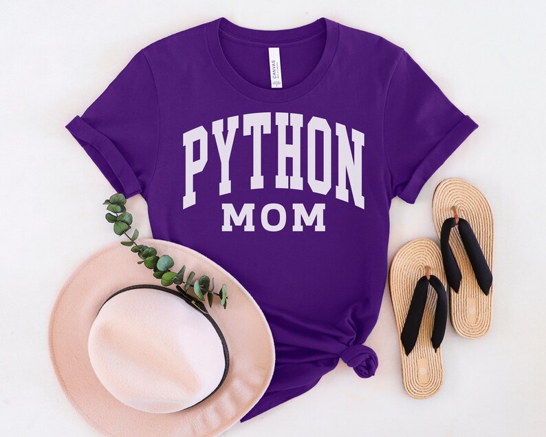 Peut inclure: T-shirt violet avec un texte blanc qui dit "PYTHON MOM" dans une police d'&eacute;criture universitaire.