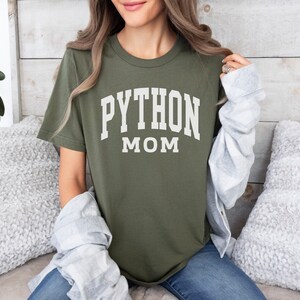Peut inclure: Un t-shirt vert avec du texte blanc qui dit "PYTHON MOM".