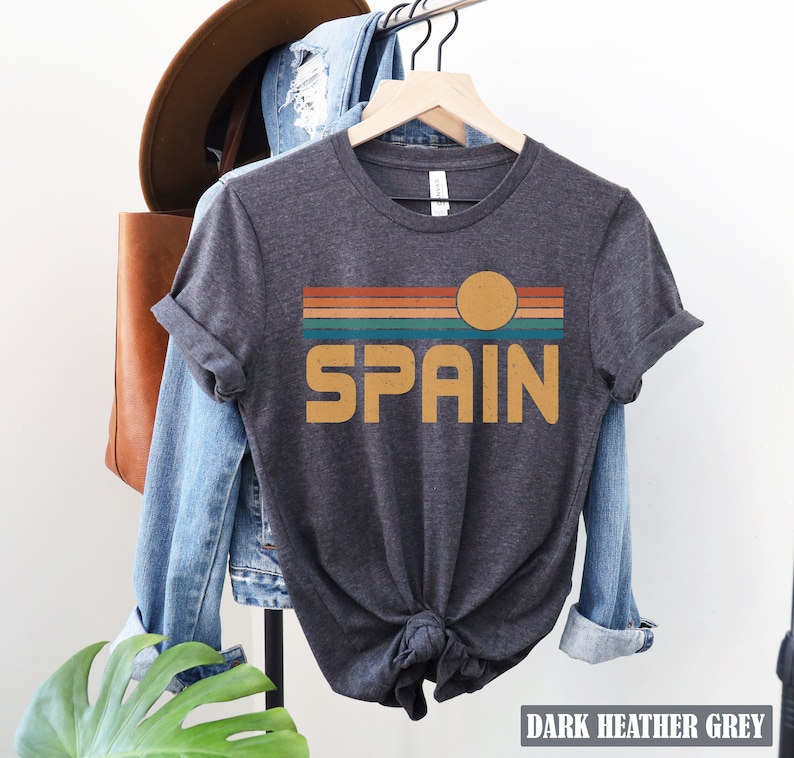 May include: Dark heather grey t-shirt with a retro sunset graphic and the word "SPAIN" in yellow.