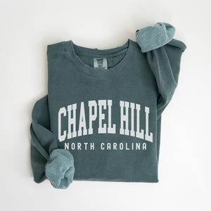 May include: A teal blue sweatshirt with the text "Chapel Hill North Carolina" in white.