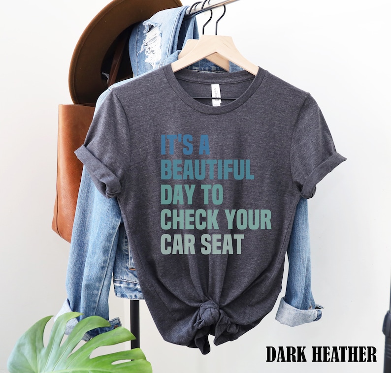 May include: Dark heather grey t-shirt with the text "It's a beautiful day to check your car seat" in a gradient of blue and green.