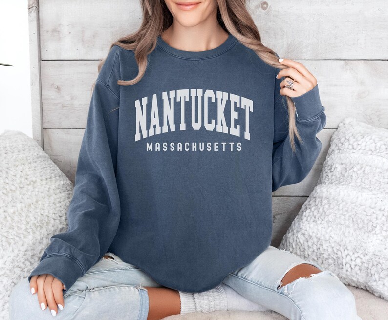 May include: A navy blue long-sleeved sweatshirt with the text "NANTUCKET MASSACHUSETTS" printed in white.