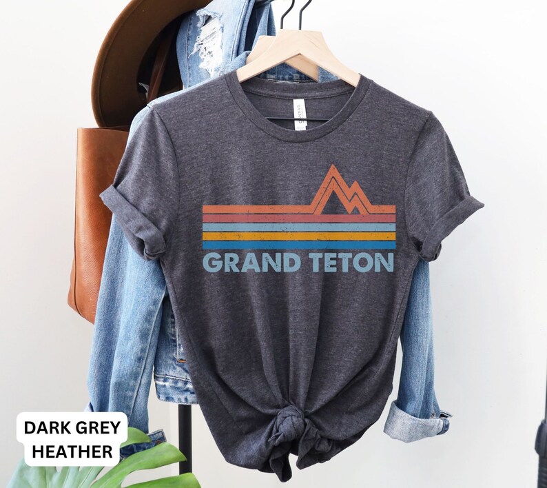 Puede incluir: Camiseta de color gris oscuro jaspeado con un gr&aacute;fico retro de monta&ntilde;as y el texto "GRAND TETON" en blanco.