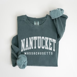 May include: A teal blue sweatshirt with the text "NANTUCKET MASSACHUSETTS" in white.