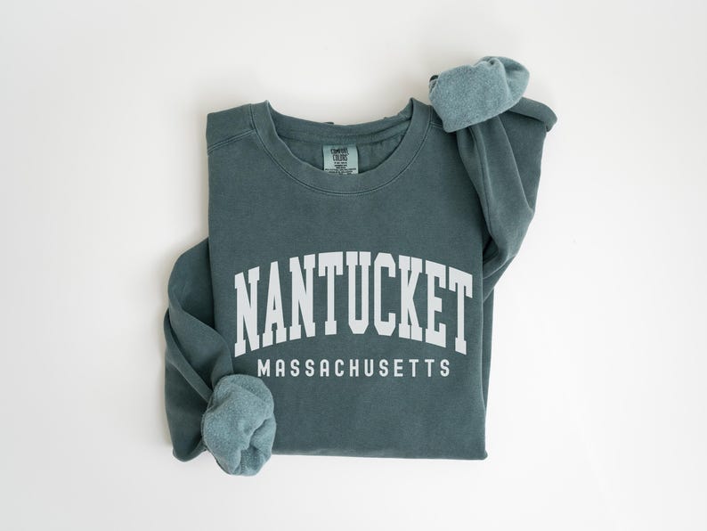 May include: A teal blue sweatshirt with the text "NANTUCKET MASSACHUSETTS" in white.