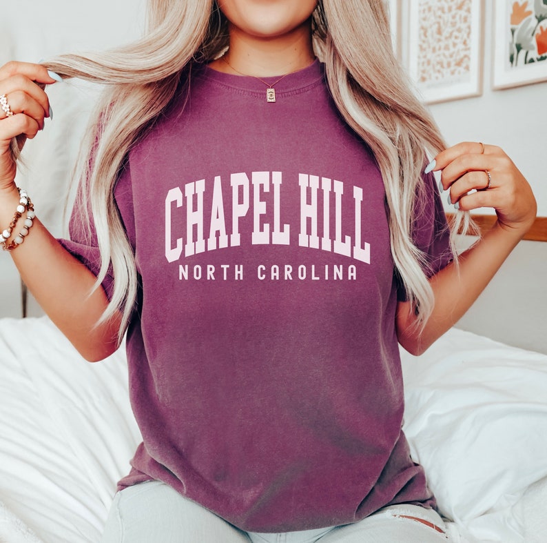 Op de afbeelding: Een paars T-shirt met de tekst "Chapel Hill North Carolina" in wit.