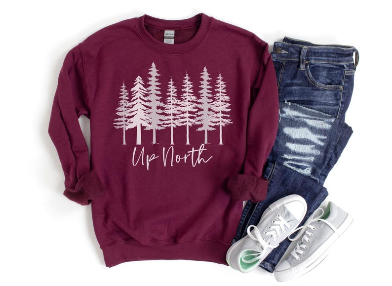 May include: A maroon sweatshirt with a white silhouette of a row of pine trees and the text "Up North" in pink lettering.