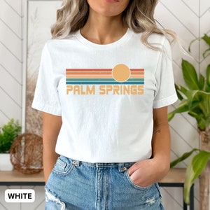 May include: White t-shirt with a retro sunset graphic and the text "PALM SPRINGS" in a vintage font.