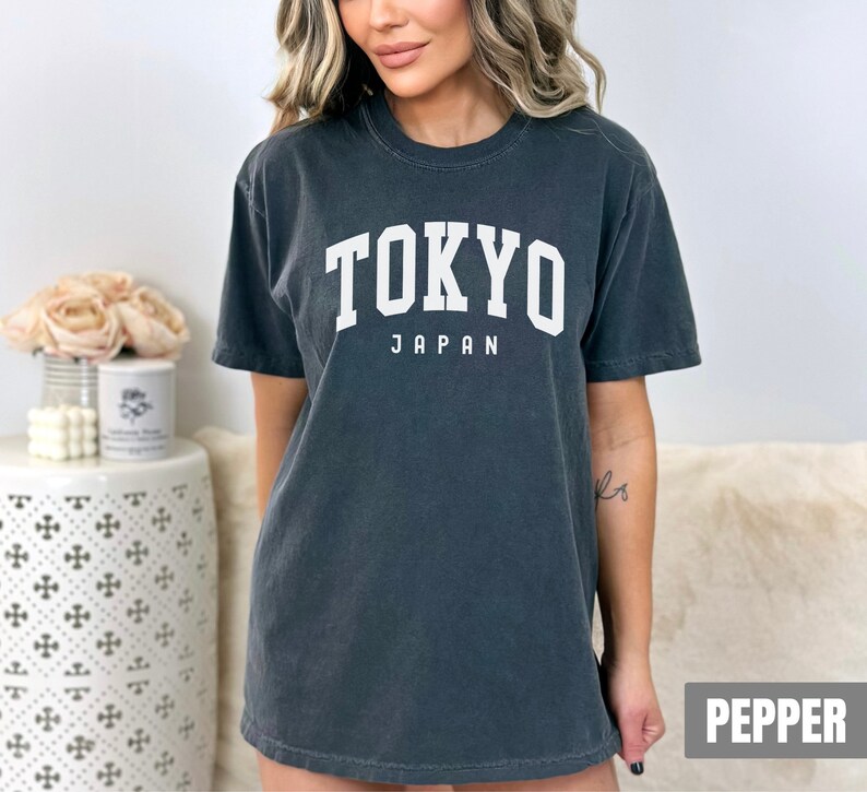 Pode incluir: Uma camiseta cinza escura com o texto "TOKYO JAPAN" impresso em branco.