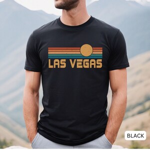 May include: Black t-shirt with a retro sunset graphic and the text "LAS VEGAS" in yellow.
